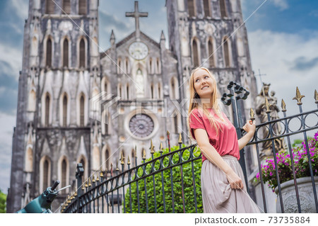 Young woman tourist on background of St Joseph's Cathedral in Hanoi. Vietnam reopens after coronavirus quarantine COVID 19 73735884