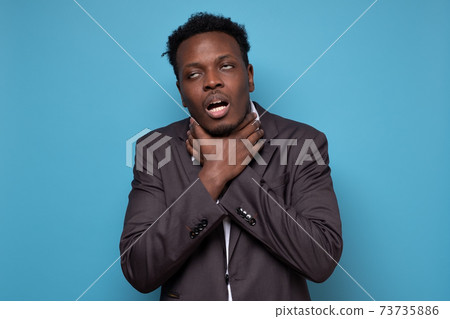 African man holding hands crossed on neck and chocking himself, feeling pain African man holding hands crossed on neck and chocking himself, feeling pain 73735886
