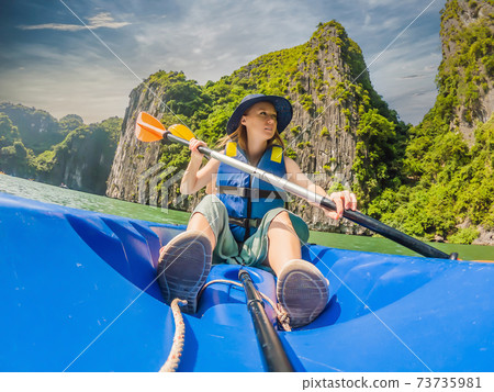 Mom, dad and son travelers rowing on a kayak in Halong Bay. Vietnam. Travel to Asia, happiness emotion, summer holiday concept. Traveling with children concept. After COVID 19. Picturesque sea 73735981