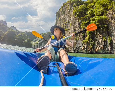 Mom, dad and son travelers rowing on a kayak in Halong Bay. Vietnam. Travel to Asia, happiness emotion, summer holiday concept. Traveling with children concept. After COVID 19. Picturesque sea 73735999