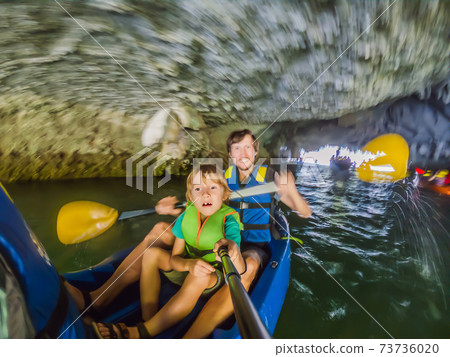 Mom, dad and son travelers rowing on a kayak in Halong Bay. Vietnam. Travel to Asia, happiness emotion, summer holiday concept. Traveling with children concept. After COVID 19. Picturesque sea 73736020