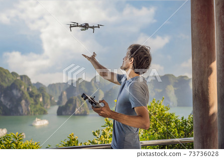 Man controls a drone in Halong Bay. Vietnam. Travel to Asia, happiness emotion, summer holiday concept. Picturesque sea landscape. Ha Long Bay, Vietnam Man controls a drone in Halong Bay. Vietnam. Travel to Asia, happiness emotion, summer holiday concept. Picturesque sea landscape. Ha Long Bay, Vietnam 73736028