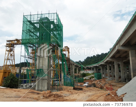 PENANG, MALAYSIA - MARCH 21, 2020: Overhead road under construction. The massive concrete column used to support the concrete road deck. Construction work is in full swing. PENANG, MALAYSIA - MARCH 21, 2020: Overhead road under construction. The massive concrete column used to support the concrete road deck. Construction work is in full swing. 73736978