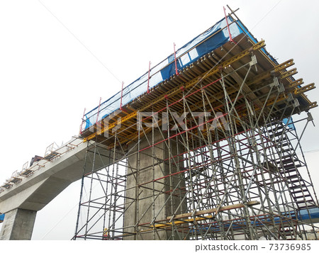 PENANG, MALAYSIA - MARCH 21, 2020: Overhead road under construction. The massive concrete column used to support the concrete road deck. Construction work is in full swing. PENANG, MALAYSIA - MARCH 21, 2020: Overhead road under construction. The massive concrete column used to support the concrete road deck. Construction work is in full swing. 73736985