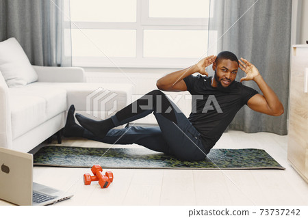 Handsome Afro American sportsman working out at home Handsome Afro American sportsman working out at home 73737242