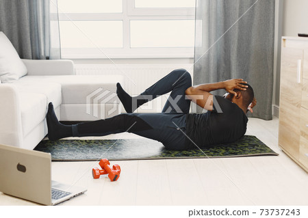 Handsome Afro American sportsman working out at home Handsome Afro American sportsman working out at home 73737243
