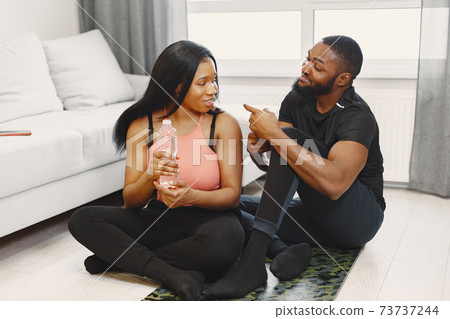 Handsome Afro American couple working out at home Handsome Afro American couple working out at home 73737244