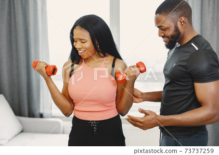 Handsome Afro American couple working out at home Handsome Afro American couple working out at home 73737259