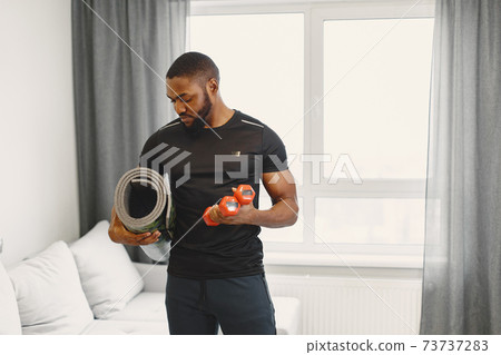Handsome Afro American sportsman working out at home Handsome Afro American sportsman working out at home 73737283