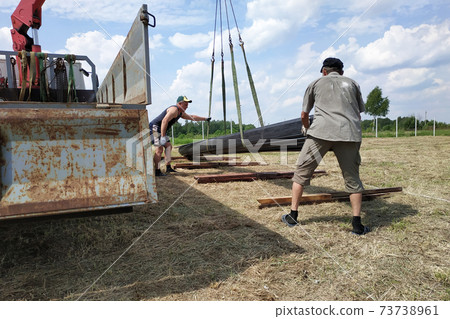 The workers support and direct the metal profile that unloads the truck crane. 73738961
