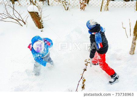 happy children playing snowballs, two brothers enjoying winter vacation, energetic game in the snow. 73738963