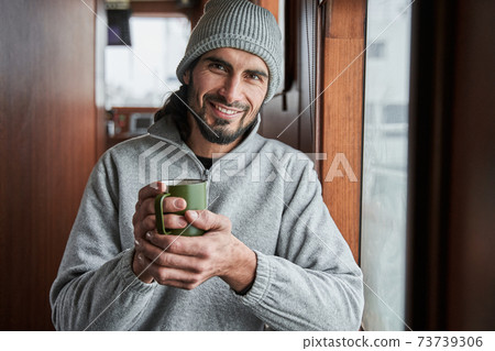 Fisherman holding cup and standing at the boat during the work 73739306