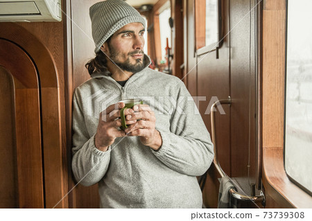 Fisherman standing inside of the boat and drink hot tea Fisherman standing inside of the boat and drink hot tea 73739308
