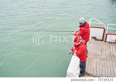Sailor helping to the diligent fisher to taking out huge fish 73739325