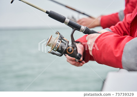 Two fishermans holding fishing rod to fighting fish 73739329