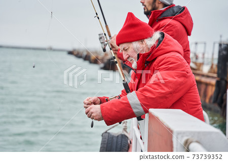 Colleagues standing on a boat with fishing rod and hook the bait Colleagues standing on a boat with fishing rod and hook the bait 73739352