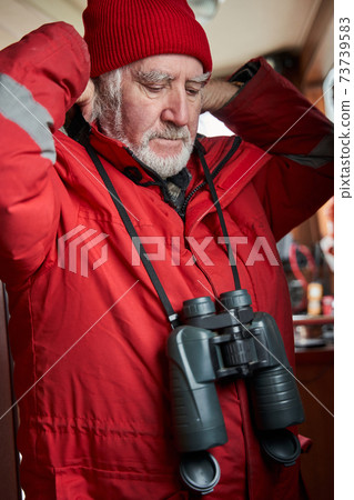 Sailor hanging binoculars on his neck inside the boat 73739583