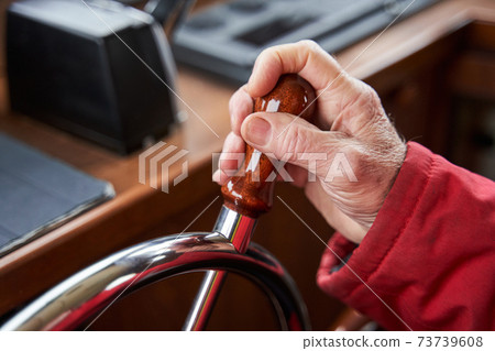 Man holding hands on ship rudder and navigates 73739608