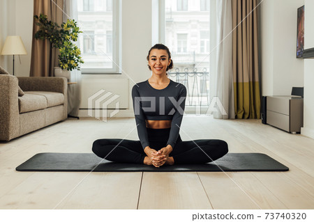Beautiful smiling woman sitting on a mat at home 73740320