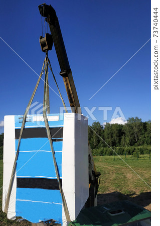 The mobile crane unloads pallets of blocks from the trailer of the truck. 73740444