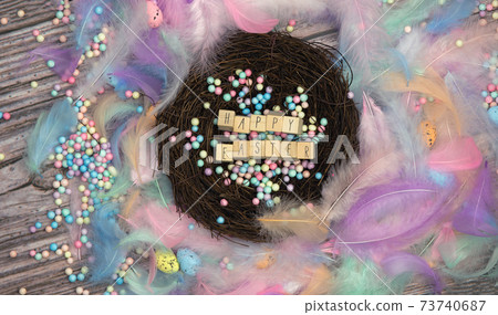 Colorful Easter eggs in bird nest surrounded with pastel colored feathers and wooden cubes with the text Happy Easter top view, modern background design, Easter holliday, Spring, concept Colorful Easter eggs in bird nest surrounded with pastel colored feathers and wooden cubes with the text Happy Easter top view, modern background design, Easter holliday, Spring, concept 73740687