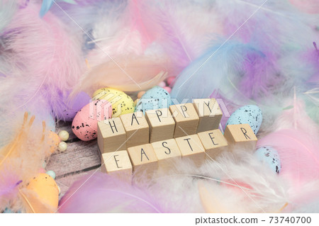 Happy Easter written with wooden cubes surrounded with beautiful pastel colored decorative feathers and eggs, April, Easter, Religion, Spring concept for background and greeting card top view Happy Easter written with wooden cubes surrounded with beautiful pastel colored decorative feathers and eggs, April, Easter, Religion, Spring concept for background and greeting card top view 73740700