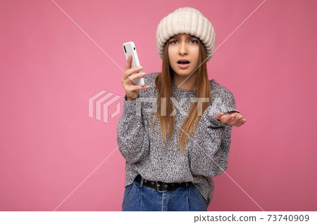Beautiful shocked dissatisfied young blonde woman wearing casual grey sweater and beige hat isolated 73740909