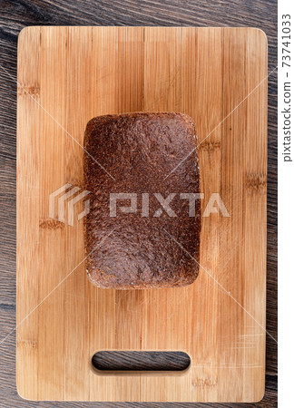 Top view of rye bread on a wooden cutting board. Top view of rye bread on a wooden cutting board. 73741033