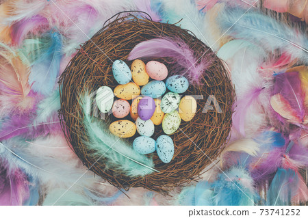 Colorful Easter eggs in bird nest surrounded with pastel colored feathers and wooden cubes with the text Happy Easter top view, modern background design, Easter holliday, Spring, concept Colorful Easter eggs in bird nest surrounded with pastel colored feathers and wooden cubes with the text Happy Easter top view, modern background design, Easter holliday, Spring, concept 73741252