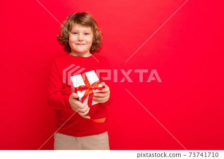 Photo shot of joyful smiling blonde curly boy isolated over red background wall wearing red sweater 73741710