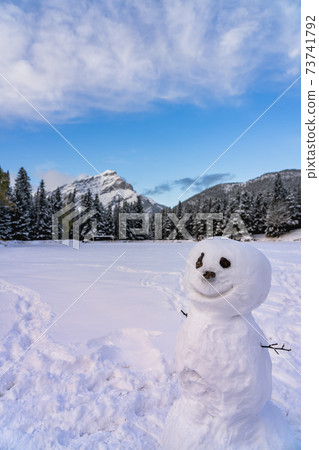 A smiling snowman in the snowy playground. Cascade Mountain and trees in the background. Banff National Park, Canadian Rockies. A smiling snowman in the snowy playground. Cascade Mountain and trees in the background. Banff National Park, Canadian Rockies. 73741792