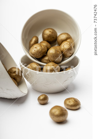White ceramic bowl full of chocolate pralines. Sweet truffles with cinamon, cardamom and clove on a white isolated background. 73742476