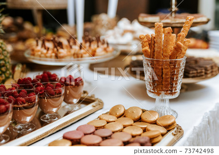 Closeup of a wedding candybar with cakes and fruits Closeup of a wedding candybar with cakes and fruits 73742498