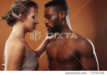Young pretty couple diverse races together posing sensitive on brown background, lifestyle people concept Young pretty couple diverse races together posing sensitive on brown background, lifestyle people concept 73742784