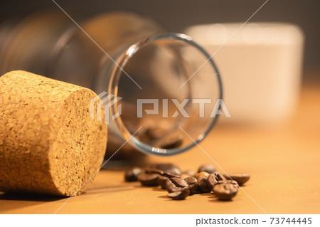Roasted coffee beans on table with jar Roasted coffee beans on table with jar 73744445