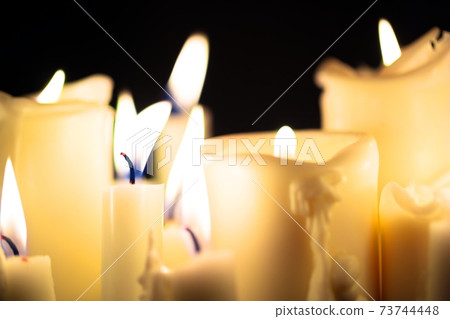 Candles glowing against dark background Candles glowing against dark background 73744448