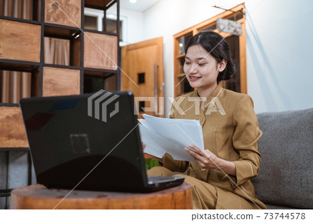 woman civil servant working from home using laptop computer and worksheets sitting 73744578