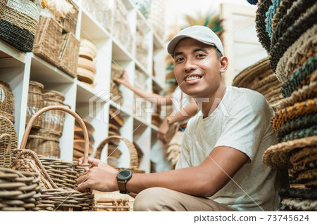 craft buyer holding a woven basket bag and smiling at camera craft buyer holding a woven basket bag and smiling at camera 73745624