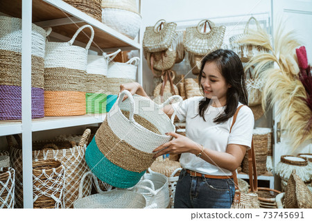 Asian woman raises wicker baskets standing among the handicraft items Asian woman raises wicker baskets standing among the handicraft items 73745691