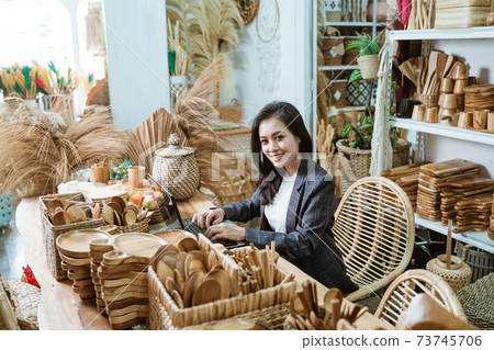 smiling woman craft designer looks at the camera while using a laptop on the desk smiling woman craft designer looks at the camera while using a laptop on the desk 73745706