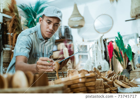 man holds a craft item and clipboard while checking items among craft items man holds a craft item and clipboard while checking items among craft items 73745717