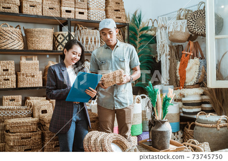 woman holds the clipboard and the man holds the wicker box while checking items woman holds the clipboard and the man holds the wicker box while checking items 73745750