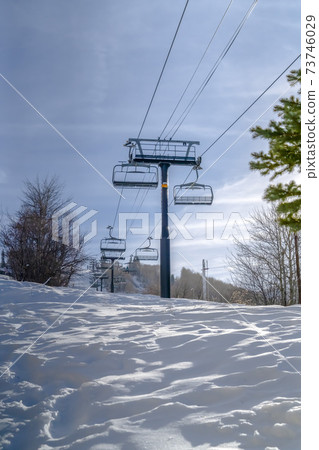 Sunlit snow under ski lifts and peaceful blue sky 73746029
