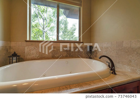 Interior view of a bathroom with close up of the gleaming bathtub and faucet Interior view of a bathroom with close up of the gleaming bathtub and faucet 73746043
