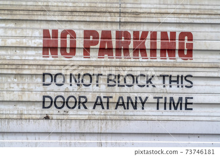 Close up of a corrugated metal door with a painted No Parking sign Close up of a corrugated metal door with a painted No Parking sign 73746181