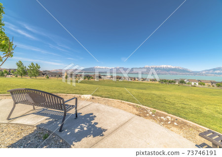 Park metal bench with view of lake snowy timpanogos mountains and blue sky Park metal bench with view of lake snowy timpanogos mountains and blue sky 73746191