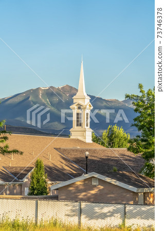 Exterior view of a church with white spire seen against mountain and blue sky Exterior view of a church with white spire seen against mountain and blue sky 73746378