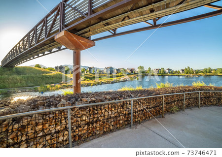 Pathway leading to a bridge that crosses over a lake with houses near the shore 73746471