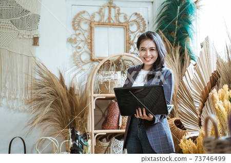 woman using a laptop while standing against a wall handicraft background woman using a laptop while standing against a wall handicraft background 73746499