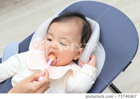 Baby feeding baby food in the living room 73746967